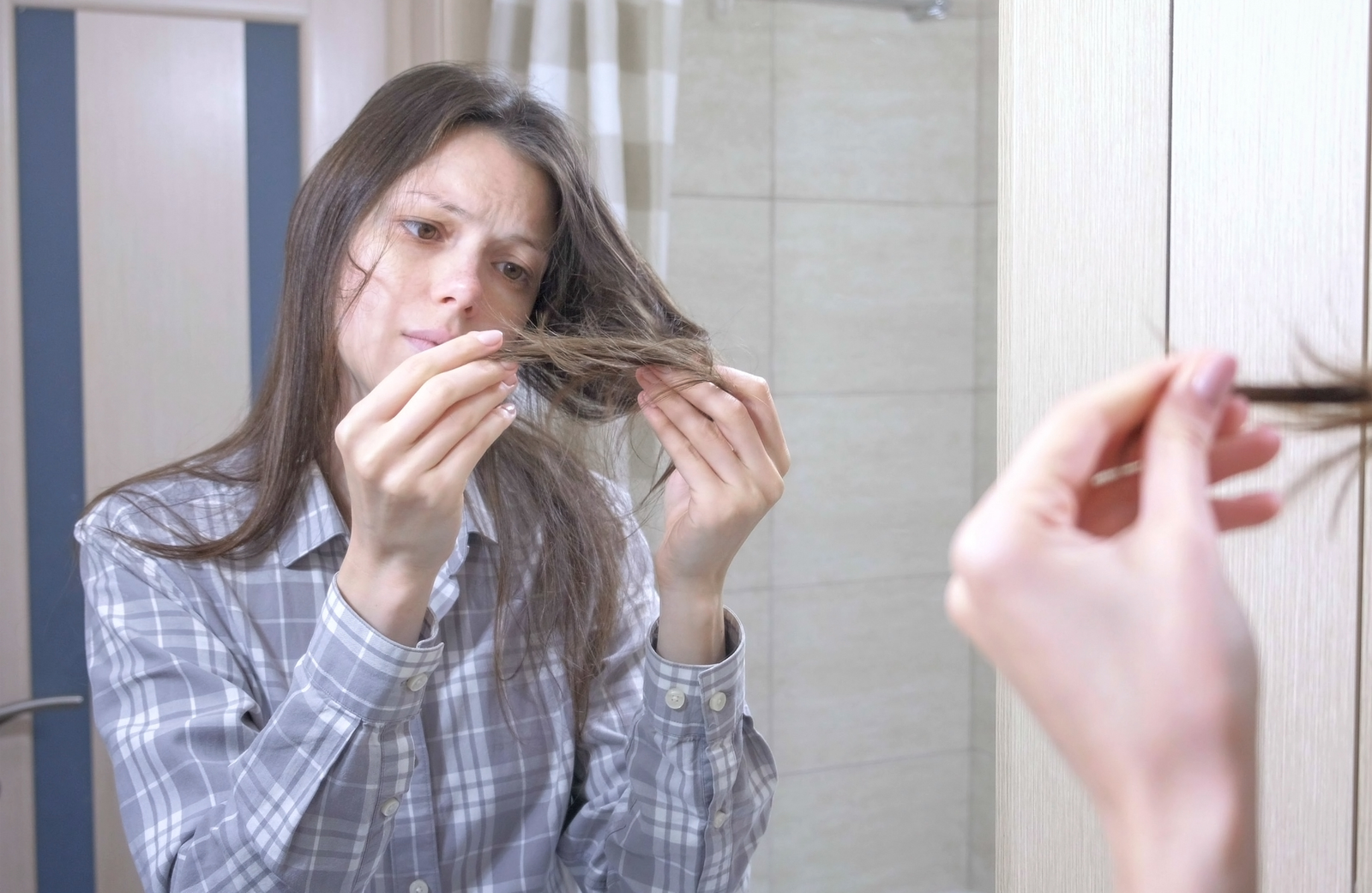 Mujer mostrando su cabello quebradizo por falta de agua de manzanilla para el pelo